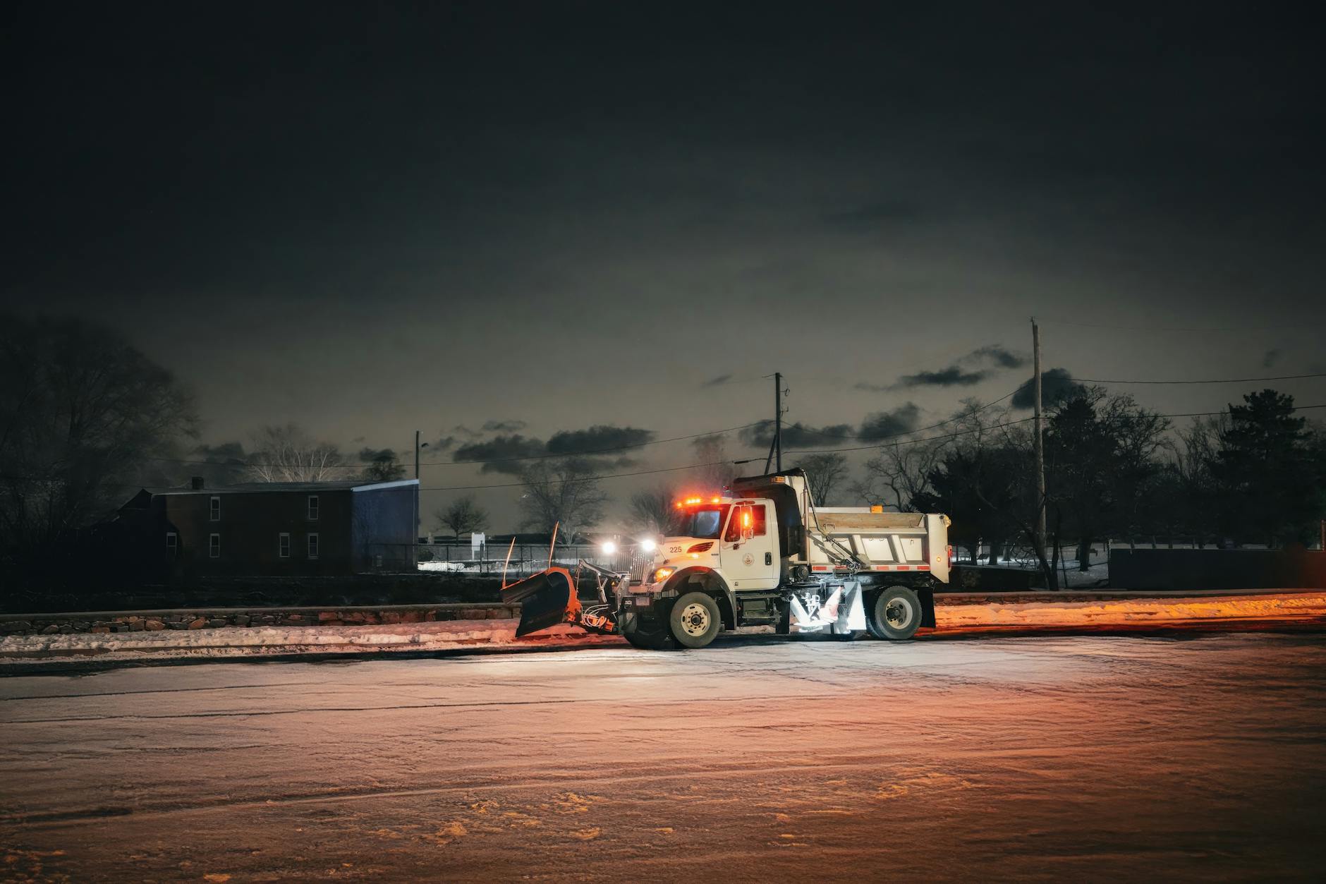 nighttime snow plow clearing urban street scene