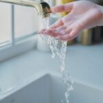 woman putting her hand under water flowing from the kitchen tap