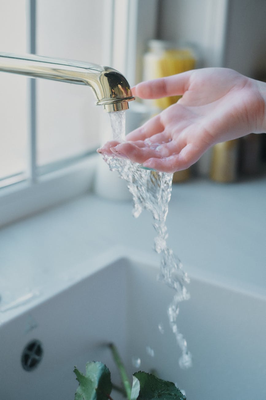 woman putting her hand under water flowing from the kitchen tap