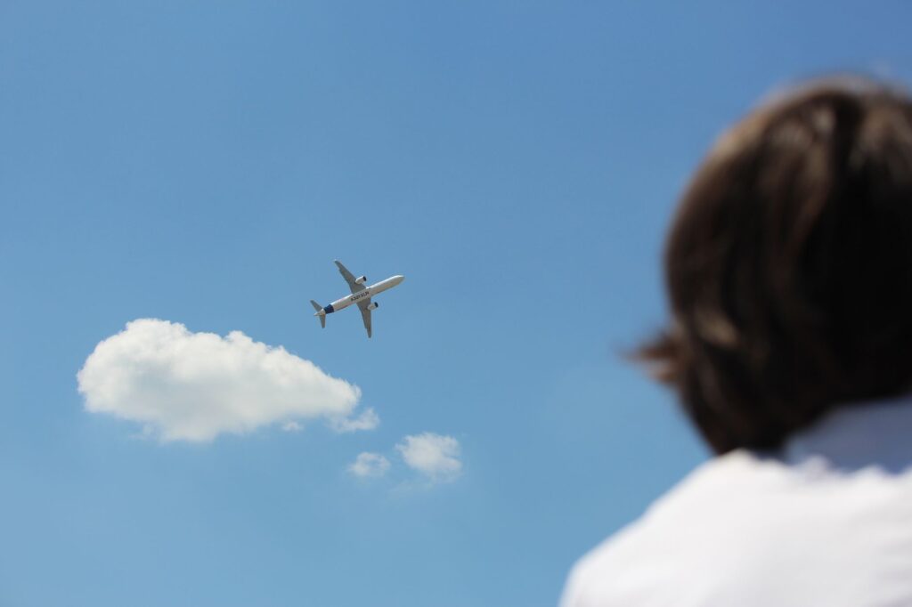 airplane soaring in clear blue sky with observer