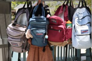 colorful backpacks hanging on hooks outdoors